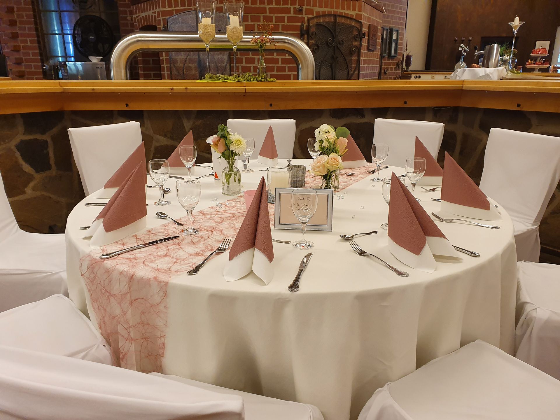 Rosa gedeckter Rundtisch vor der Natursteinbar