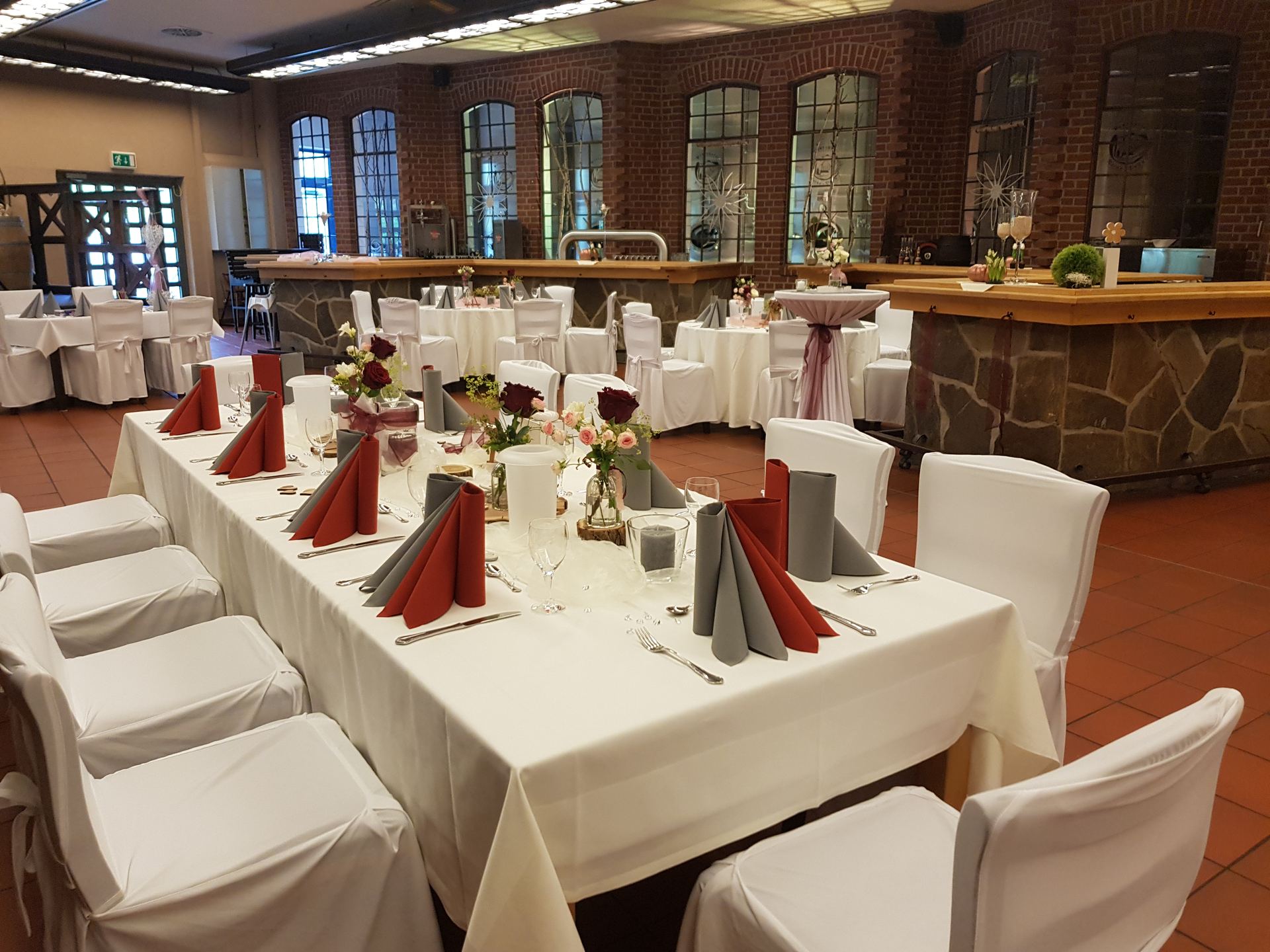 Festsaal mit rot-grauen Servietten und eleganter Tischdekoration